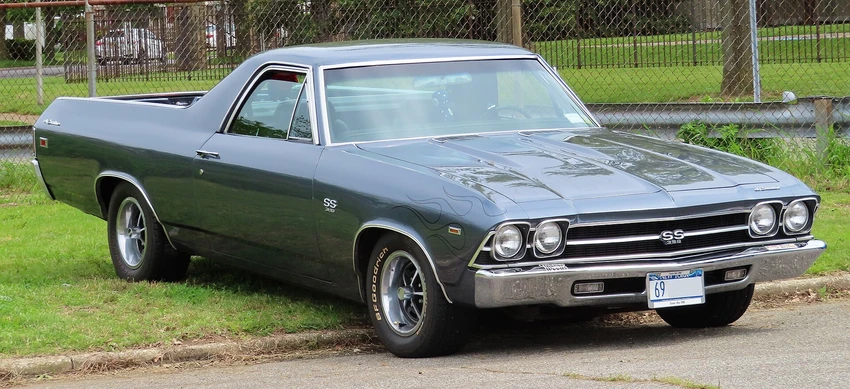 A gray El Camino car poorly parked on grass.