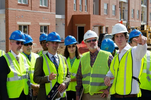 A group of people in construction vests and hats look off camera.