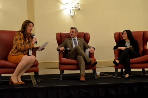 Three people sit in chairs talking.