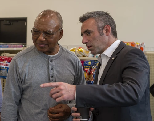 A talks to another man while pointing off camera.