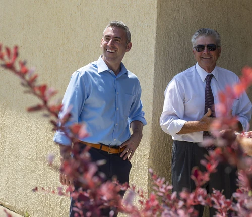 Two men smile and look off camera.
