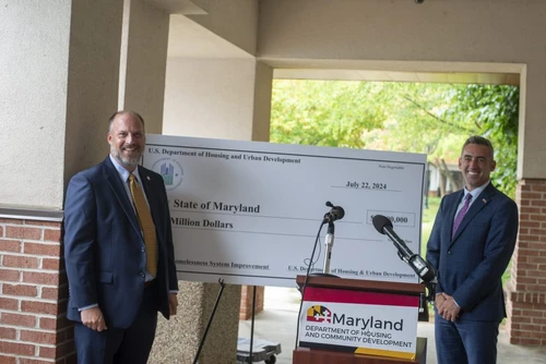 Two people pose next a giant check.