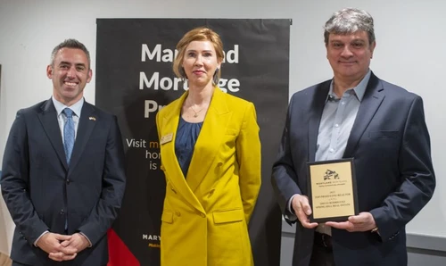 Three people pose with an award.