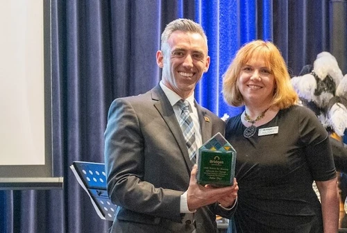 A man a woman smile holding a award.