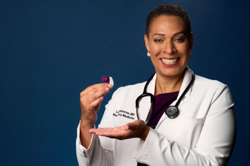 A smiling women, Elizabeth Clayborne, with a lab coat holding NasaClip.