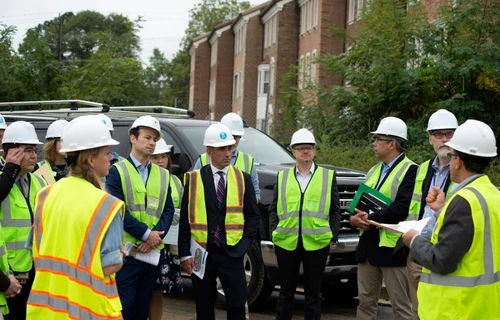 A group of people with high visibility vests and hard hats talking.