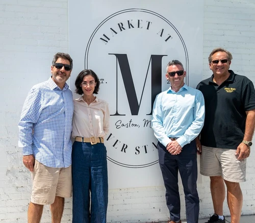 A group of people posing in front of a sign.