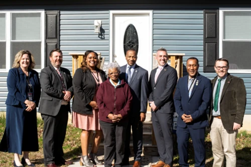 Groups of people posing in front of a house.
