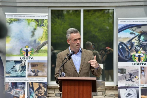 A man speaks at a podium outside.