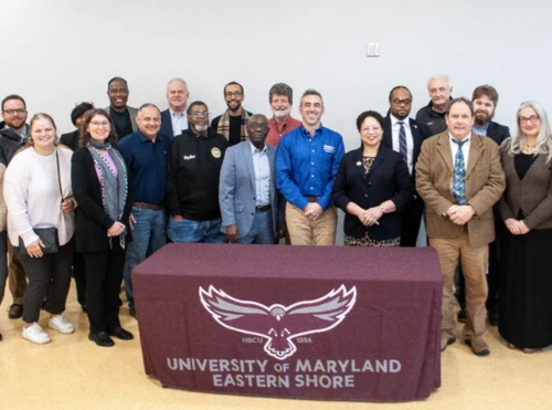 A group of people stand in front of a sign for The University of Maryland Eastern Shore.