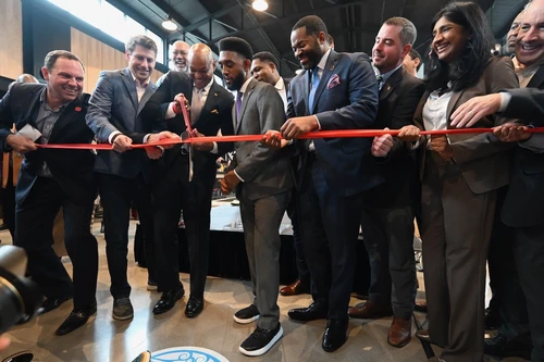 A group of people in business clothes cut a red ribbon with scissors. 