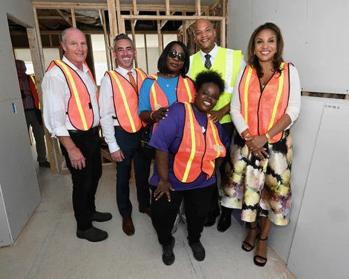 A group of people smiling wearing high visibility vests.