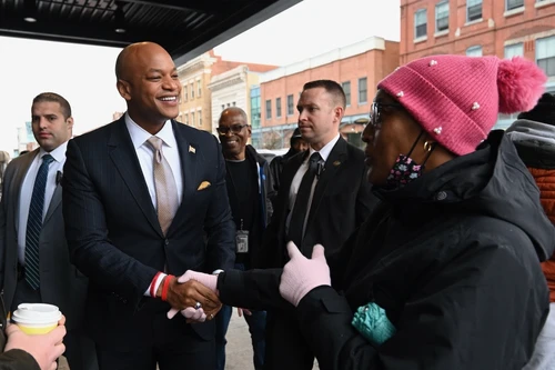 A man in a suit shakes hands with a woman.