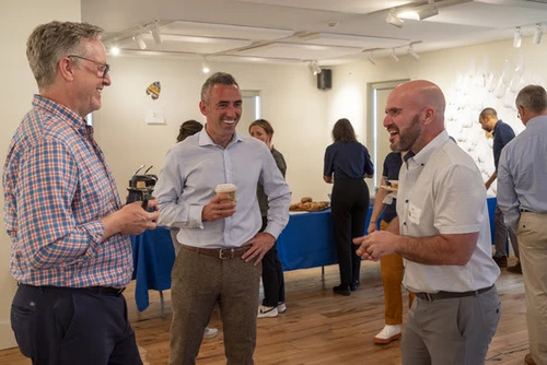 Three men talk inside a building.