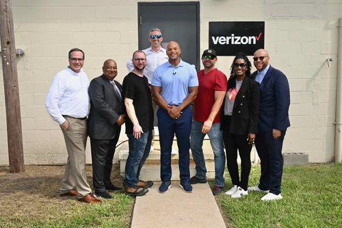 A group of people pose in front of a Verizon building.