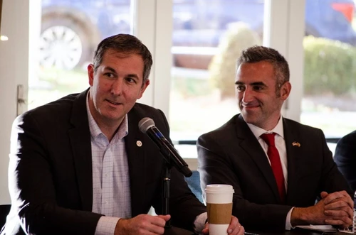 Two men speaking in front of a microphone.