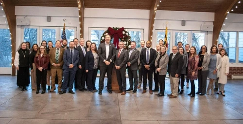 A group of people posing in front of a Christmas wreath.