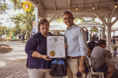 Two people pose next to an award.