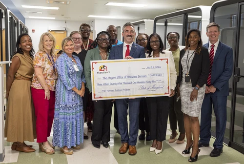 Secretary Day poses for a photo with the Mayor's Office of Homeless Solutions. He is holding a ceremonial "big check."