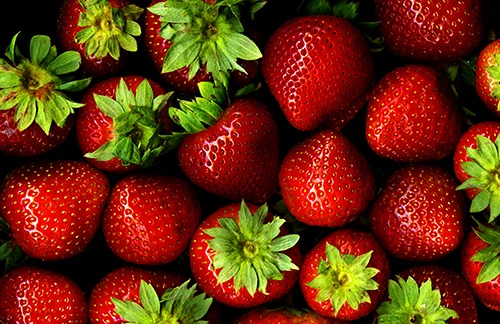 group of strawberries, some with green leaf tops