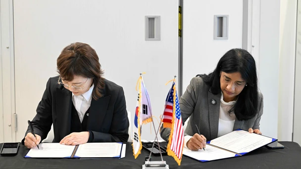 Maryland Lt. Governor Miller and Vice Governor of Gyeongsangbuk-do Province Geum-hee Yang sit at a table signing the MOU at the Quantum World Congress.