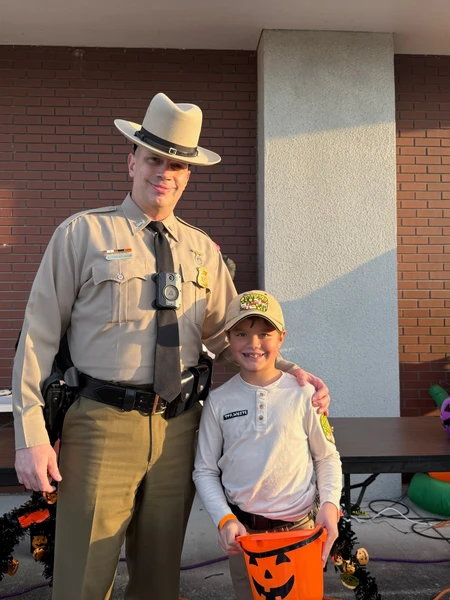 Maryland State Trooper with his arm around a little girl during halloween