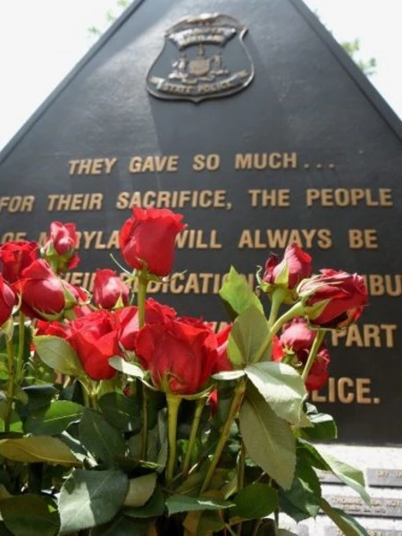 A memorial to Maryland State Police Troopers killed in the line of duty with roses in front.
