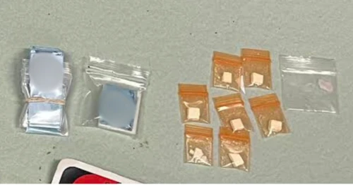 8 baggies of drugs are on a gray background, suspected heroin and cocaine 