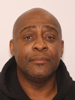 A man with a shaved head and a short beard looks directly at the camera with a neutral expression.