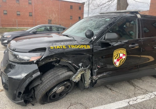 Damaged black state trooper SUV with Maryland State Police emblem and visible front-end damage