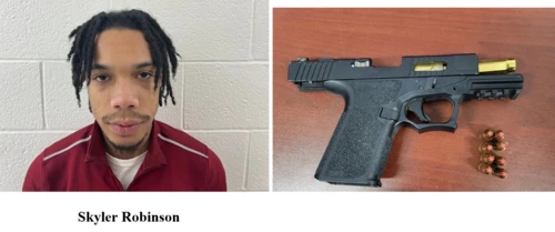 A male on the left wearing a red shirt stands in front of a cinderblock wall, on the right, a handgun. 