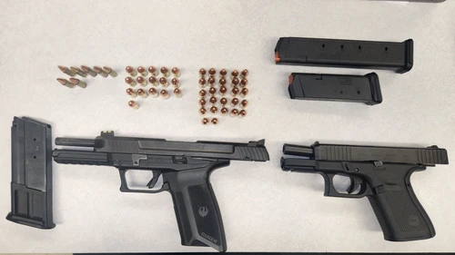 Two black handguns with ammo and extra magazines on a white background.
