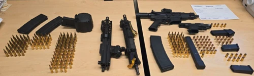 Guns laying on a wood table. 