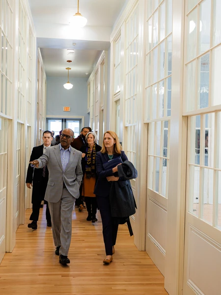 A group of people walking down a well-lit hallway with glass-paneled doors at PS 103.