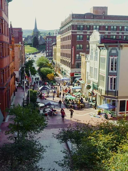 View of Baltimore Street in Cumberland, with historic buildings, people, and a distant church spire.