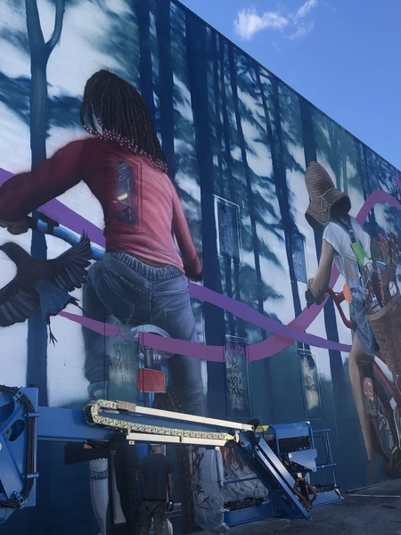 Mural of two people on bicycles surrounded by trees and birds.