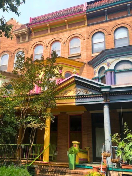 Row of historic townhouses with colorful architectural details and a vibrant porch.