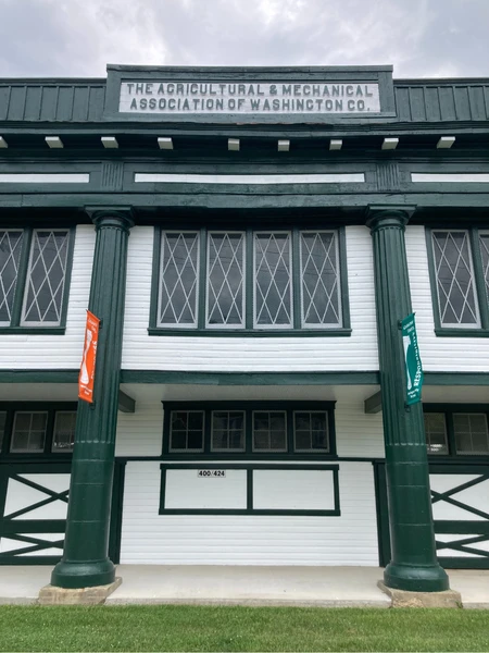 Historic building with green columns and a white facade, featuring the text "The Agricultural & Mechanical Association of Washington Co."