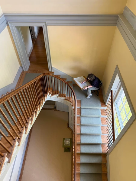 Overhead view of a staircase and person sketching in a hallway.