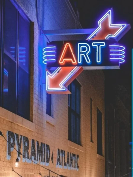 A neon "ART" sign with blue and red lighting on the side of the Pyramid Atlantic building at night.