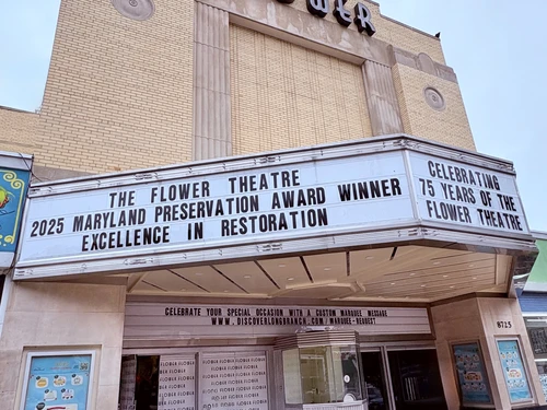 Facade of the Flower Theatre with an art deco design and a marquee displaying event information.