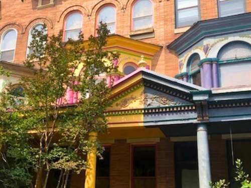 Row of historic townhouses with colorful architectural details and a vibrant porch.