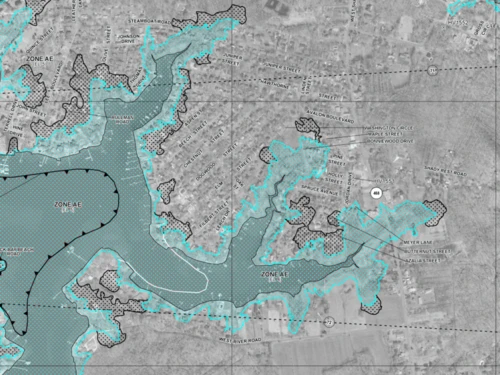 Map showing flood zones marked in blue over a grayscale aerial view.