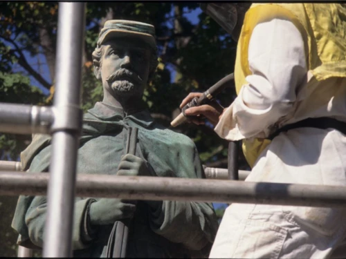 Monument of Union soldier with a person with a yellow vest on performing conservation work.