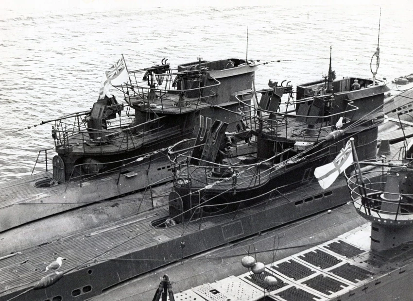 Black and white photo of the U-1105 and another submarine flying the White Ensign, focusing on their raised deck structures.