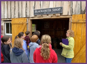 Group of people outside of a blacksmith shed.