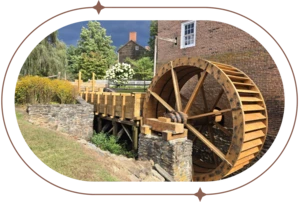 Historic grist mill in front of a brick building.