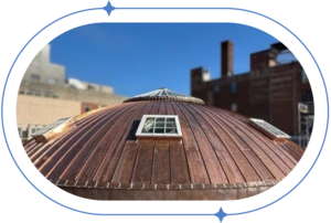 Copper clad dome roof with skylights against blue sky.