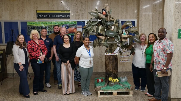 Administrator Nizer gathers with employees in front of the recycled art contest winner