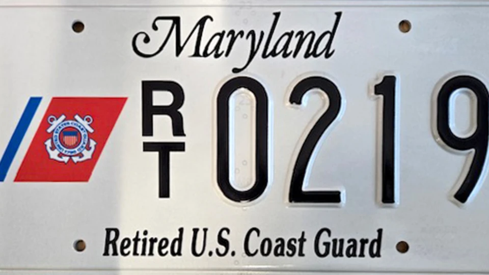 White license plate with the Coast Guard seal to the left of the plate number.